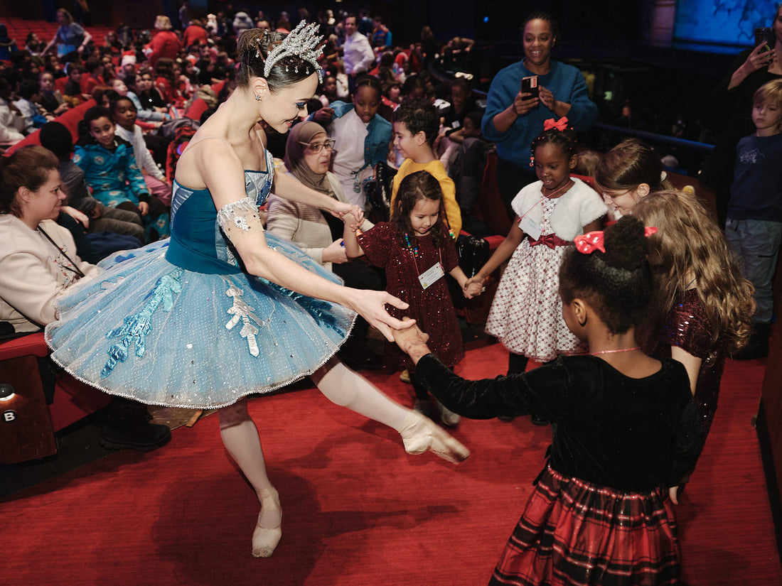 Une ballerine danse avec des enfants dans la salle lors d'une représentation de Casse-Noisette