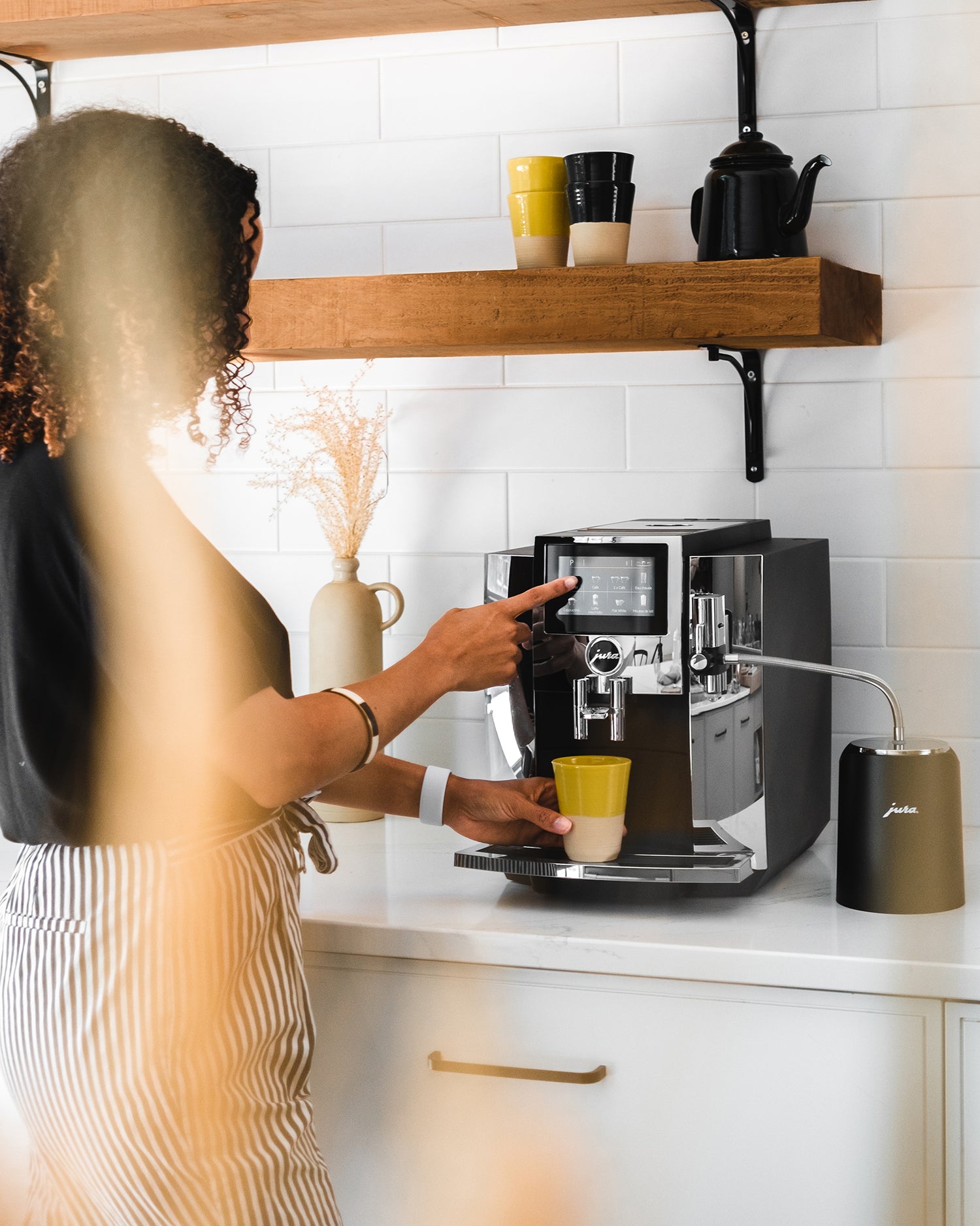 Femme préparant un café sur JURA S8 Chrome dans sa cuisine